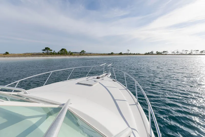 Slide: The Image of Bow view of 2000 Cabo 35 Express yacht approaching a scenic shoreline. - 34