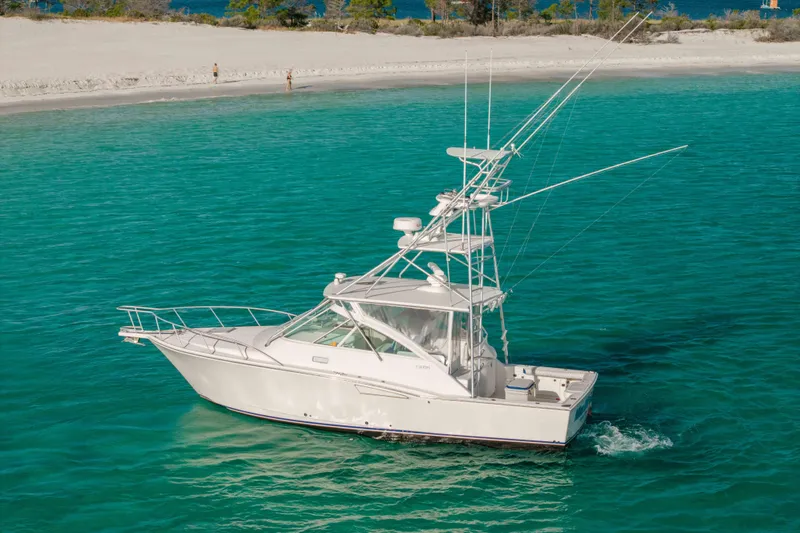 Slide: The Image of 2000 Cabo 35 Express boat cruising in clear turquoise waters near a sandy beach. - 44