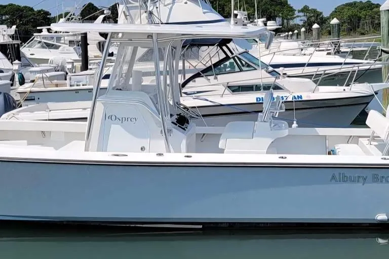 Slide: The Image of 2023 Albury Brothers 27 boat docked in a marina, surrounded by other vessels. - 2