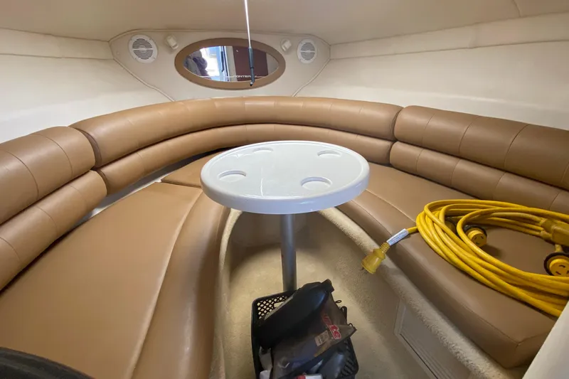 Slide: The Image of 2004 Monterey 245 Cruiser interior with brown seating, table, and coiled yellow cable. - 20