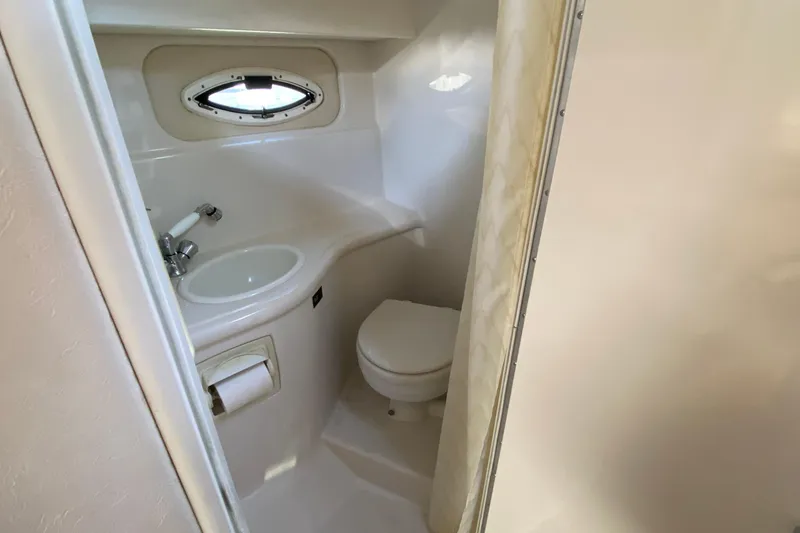 Slide: The Image of 2004 Monterey 245 Cruiser bathroom with sink, toilet, and porthole window. - 23
