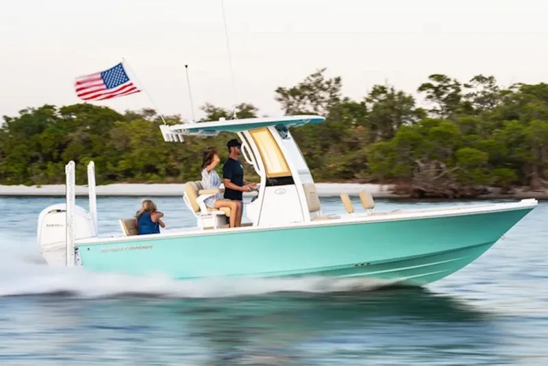 The Image of 2026 Sportsman Masters 227 Bay Boat cruising with passengers, American flag waving, scenic background. - 1