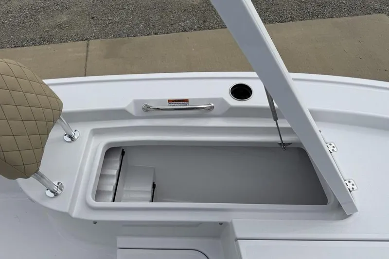 Slide: The Image of 2026 Sportsman Masters 227 Bay Boat storage compartment with beige seat and handle. - 13