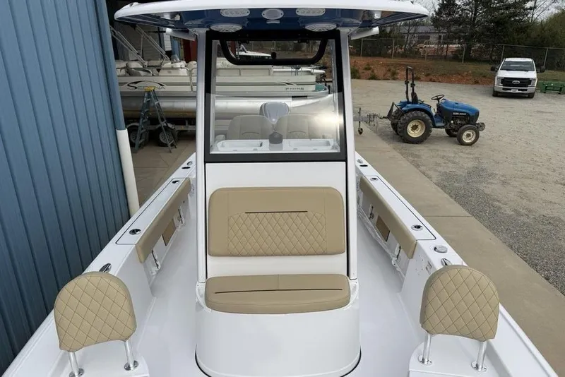 Slide: The Image of 2026 Sportsman Masters 227 Bay Boat with beige seating, docked near blue building and tractor. - 20