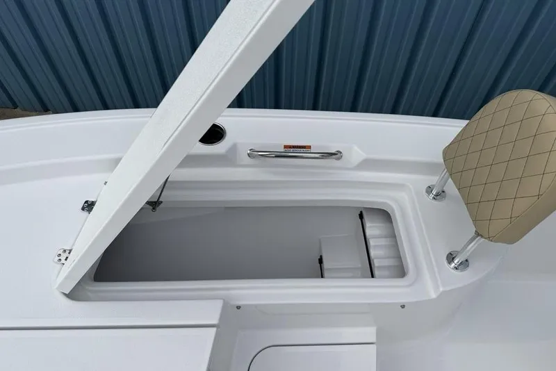 Slide: The Image of 2026 Sportsman Masters 227 Bay Boat storage compartment with open lid and cushioned seat. - 21