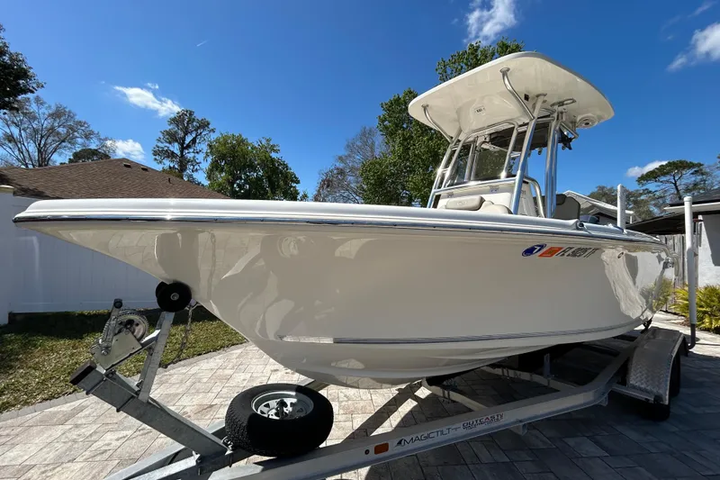 Slide: The Image of 2022 Key West 219 FS boat on trailer, parked outdoors under a clear blue sky. - 15