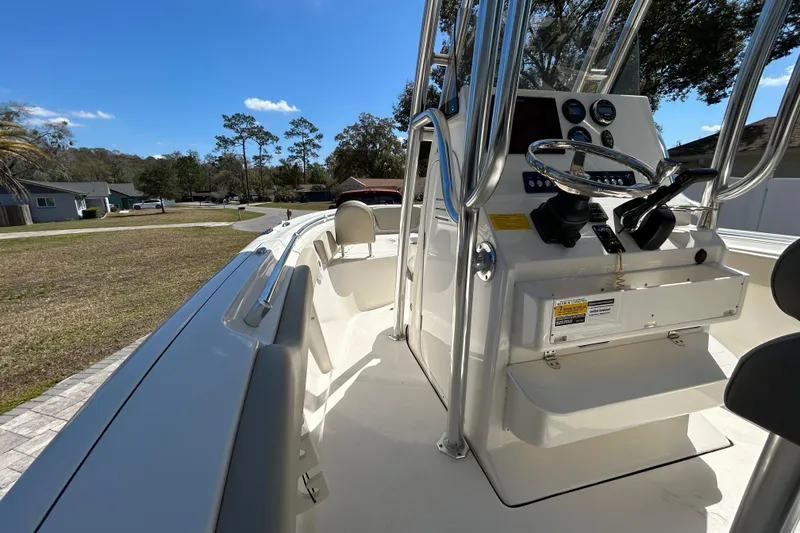 Slide: The Image of 2022 Key West 219 FS boat interior with steering console and seating, under clear blue sky. - 26