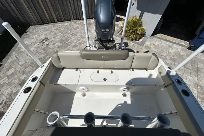 Slide: The Image of 2022 Key West 219 FS boat interior with seating and motor, parked on a paved driveway. - 51