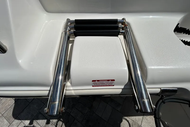 Slide: The Image of 2022 Key West 219 FS boat ladder with stainless steel rails and safety warning label. - 57