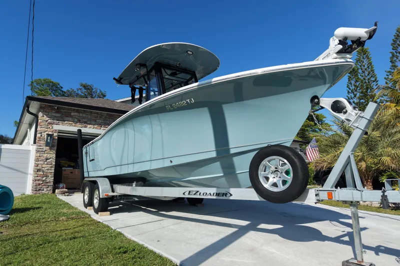 Slide: The Image of 2023 Sea Hunt Ultra 239 SE boat on trailer in driveway, sunny day. - 24