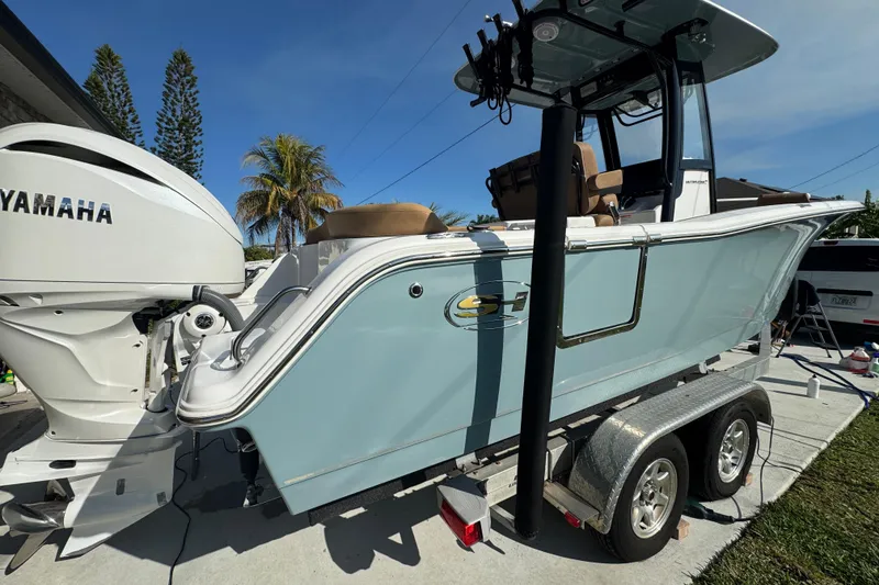 Slide: The Image of 2023 Sea Hunt Ultra 239 SE boat on trailer with Yamaha engine, parked outdoors. - 3