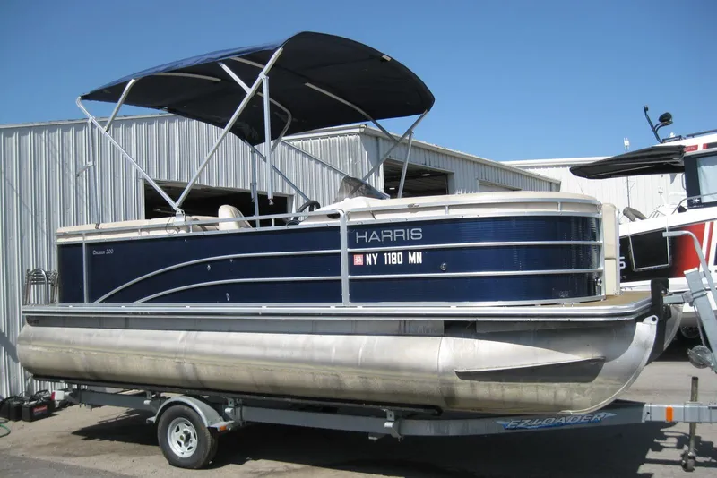 The Image of 2016 Harris FloteBote 200 Cruiser CX pontoon boat on trailer, blue and silver design. - 1