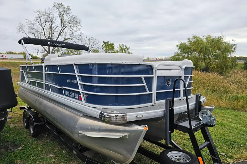 Slide: The Image of 2022 Sweetwater 2286 SFL pontoon boat on trailer, parked on grassy area. - 5