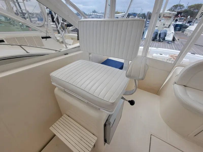 Slide: The Image of Captain's chair on 2006 Carolina Classic 32 Express boat, featuring white upholstery and footrest. - 10