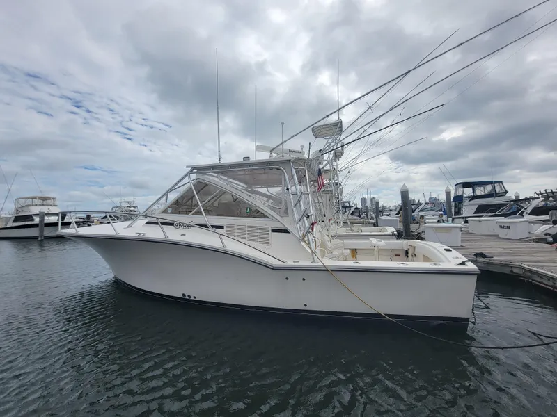 Slide: The Image of 2006 Carolina Classic 32 Express boat docked at marina under cloudy sky. - 2