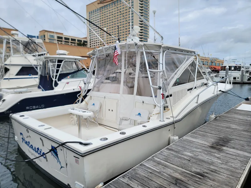 Slide: The Image of 2006 Carolina Classic 32 Express boat docked at marina, featuring enclosed cabin and fishing equipment. - 3