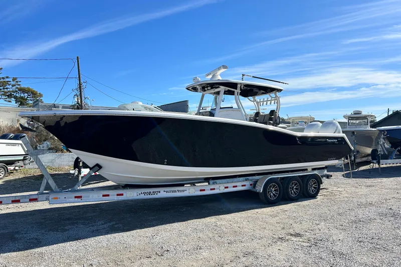 Slide: The Image of 2020 Tidewater 320 CC Adventure boat on trailer under clear blue sky. - 1