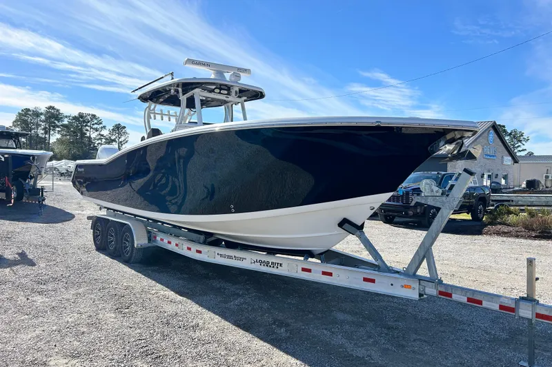Slide: The Image of 2020 Tidewater 320 CC Adventure boat on trailer under clear blue sky. - 10