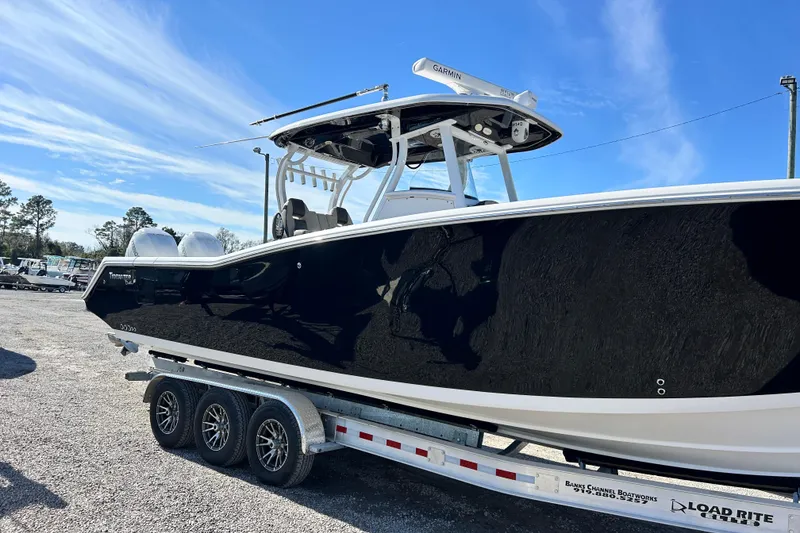 Slide: The Image of 2020 Tidewater 320 CC Adventure boat on trailer under clear blue sky. - 11