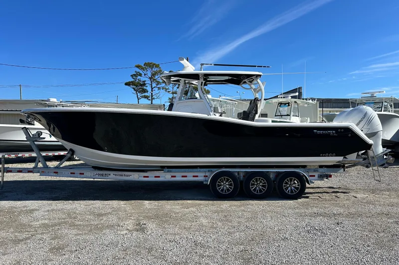 Slide: The Image of 2020 Tidewater 320 CC Adventure boat on trailer under clear blue sky. - 2