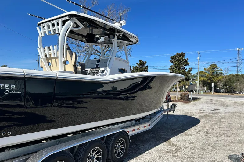 Slide: The Image of 2020 Tidewater 320 CC Adventure boat on trailer, sleek black hull, sunny day. - 8