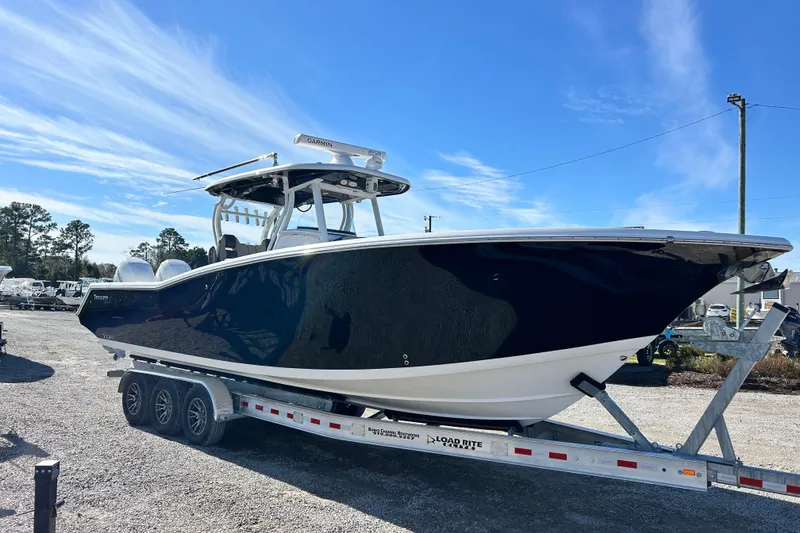 Slide: The Image of 2020 Tidewater 320 CC Adventure boat on trailer under clear blue sky. - 9