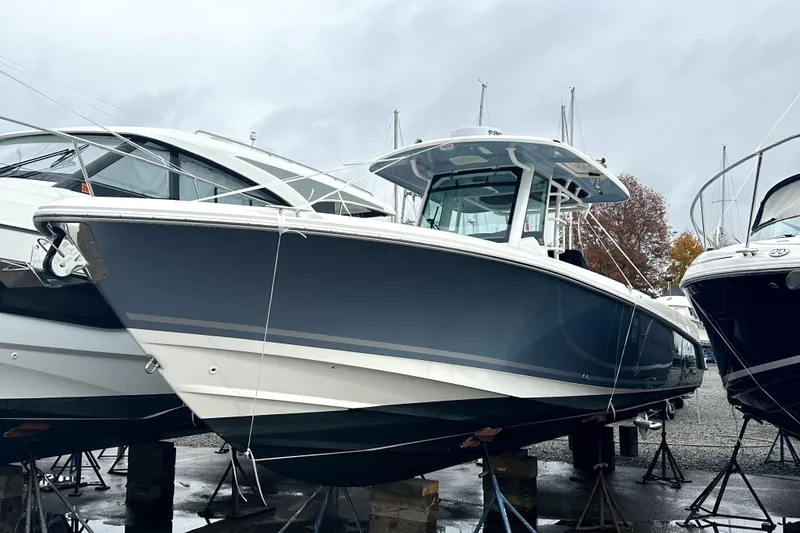The Image of 2023 Boston Whaler OUTRAGE boat on stands, displayed outdoors on a cloudy day. - 0