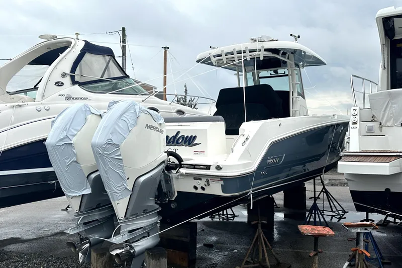 Slide: The Image of 2023 Boston Whaler OUTRAGE boat with twin Mercury engines on a dock. - 1