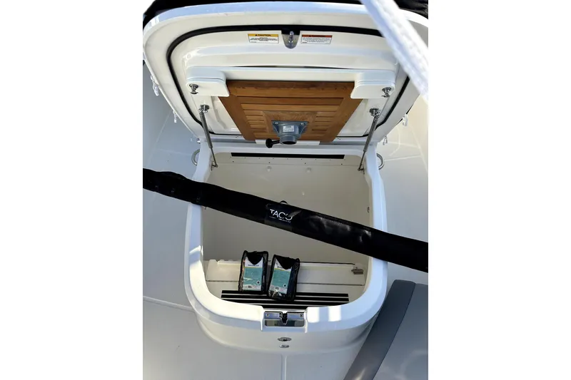 Slide: The Image of Open storage compartment on 2023 Boston Whaler OUTRAGE boat, featuring wooden panel and accessories. - 17