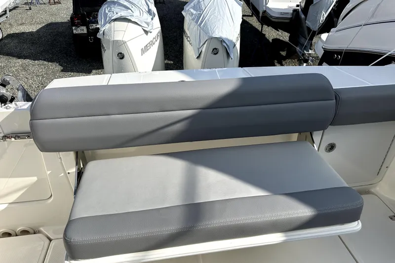 Slide: The Image of 2023 Boston Whaler OUTRAGE boat seat with gray upholstery, docked with covered engines. - 6