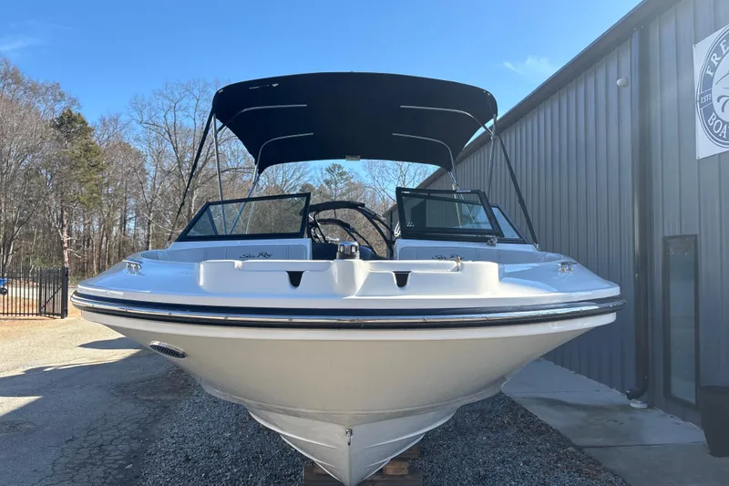 Slide: The Image of 2023 Searay SPX 210 OB boat with canopy, parked outdoors near a building. - 11