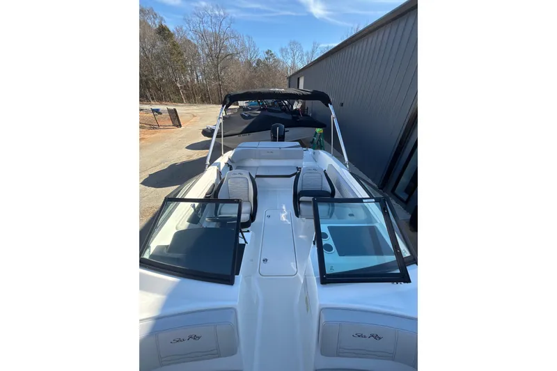 Slide: The Image of 2023 Searay SPX 210 OB boat with open deck and seating, parked outdoors. - 2