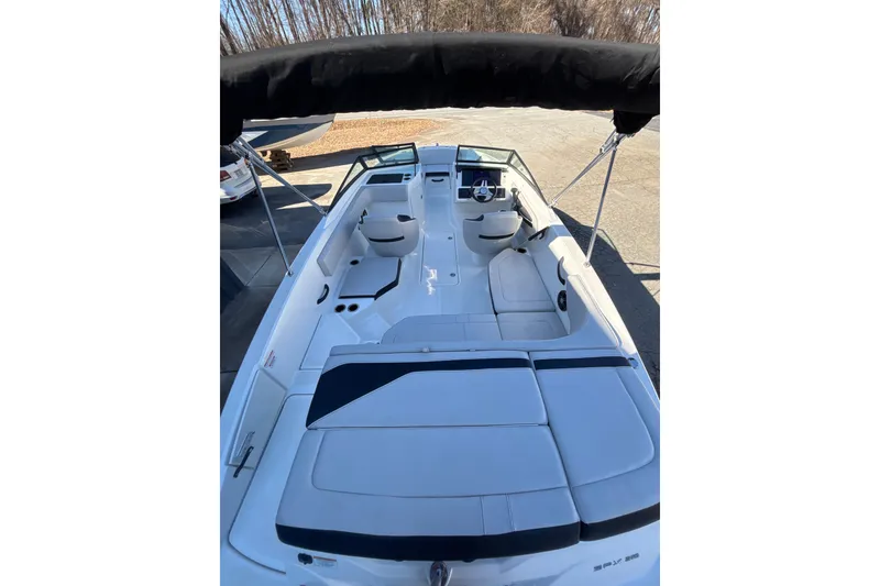 Slide: The Image of 2023 Searay SPX 210 OB boat interior with seating and steering wheel, docked outdoors. - 23