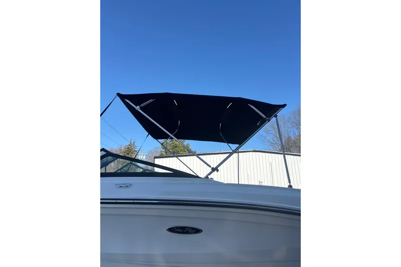 Slide: The Image of 2023 Searay SPX 210 OB boat with black canopy against clear blue sky. - 5