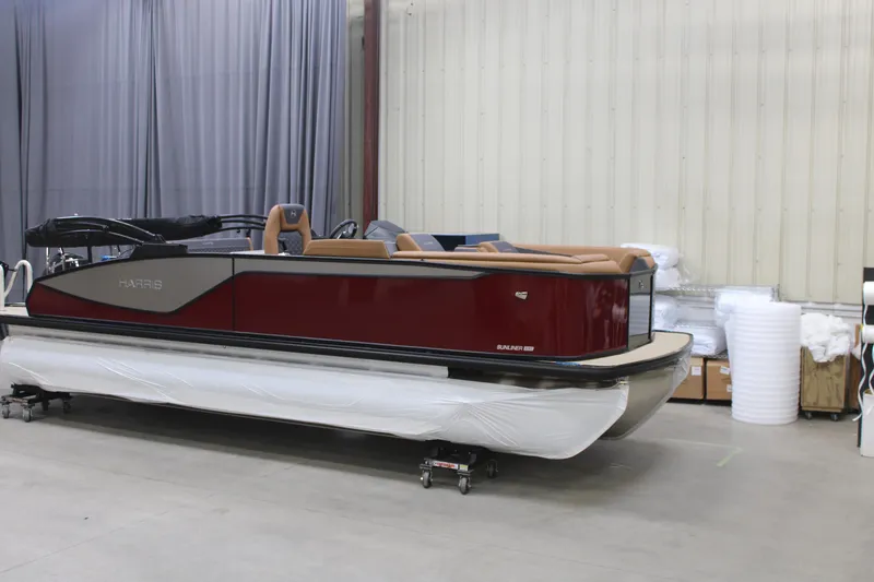 The Image of 2026 Harris Sunliner 230 pontoon boat in a showroom, featuring sleek design and luxurious seating. - 1