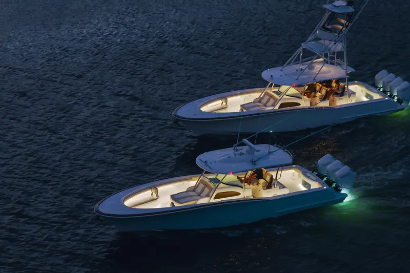 Slide: The Image of 2026 Mag Bay 38 CC boats illuminated on water at night, showcasing sleek design. - 10