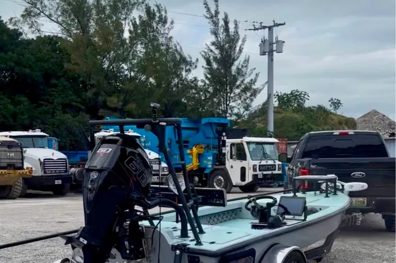 Slide: The Image of 2017 Dusky 16 Custom boat on trailer, parked near trucks in an industrial area. - 6