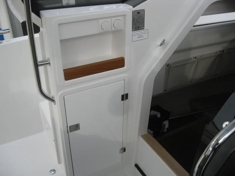 Slide: The Image of 2024 Nimbus T9 boat interior storage compartment with white cabinetry and wooden accents. - 26