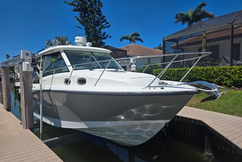 The Image of 2016 Boston Whaler 315 Conquest boat docked in a sunny residential area. - 1
