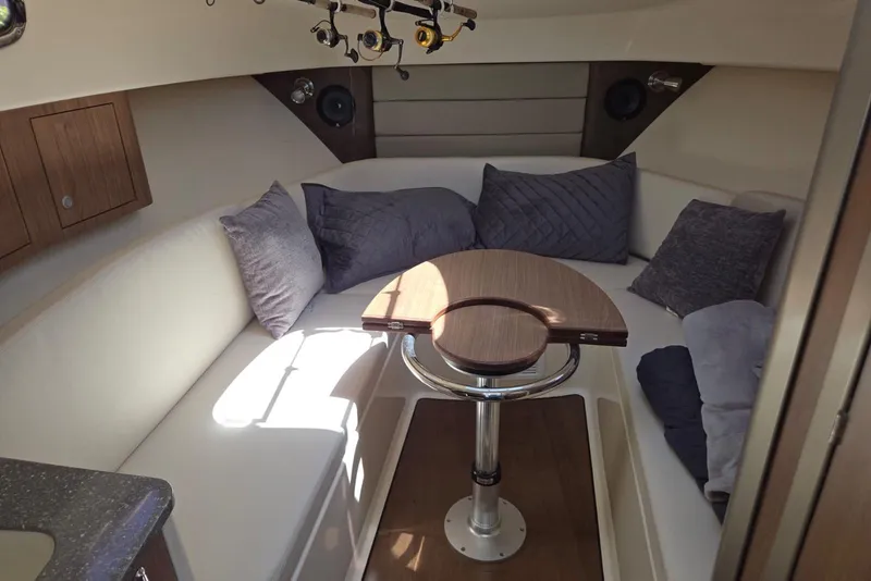 Slide: The Image of Interior of 2016 Boston Whaler 315 Conquest, featuring cozy seating and a wooden table. - 12