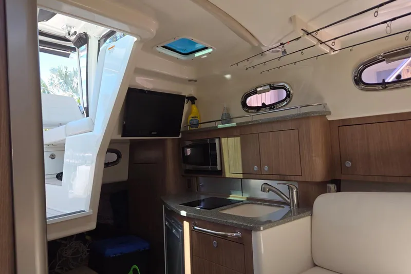 Slide: The Image of Interior of 2016 Boston Whaler 315 Conquest boat with kitchenette and seating area. - 13