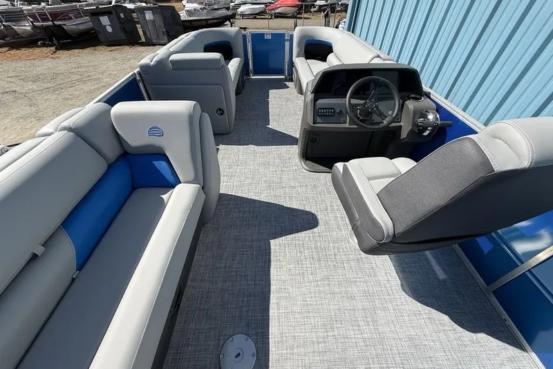 Slide: The Image of 2026 Sun Tracker Party Barge 20 DLX interior with gray and blue seating, steering console. - 24