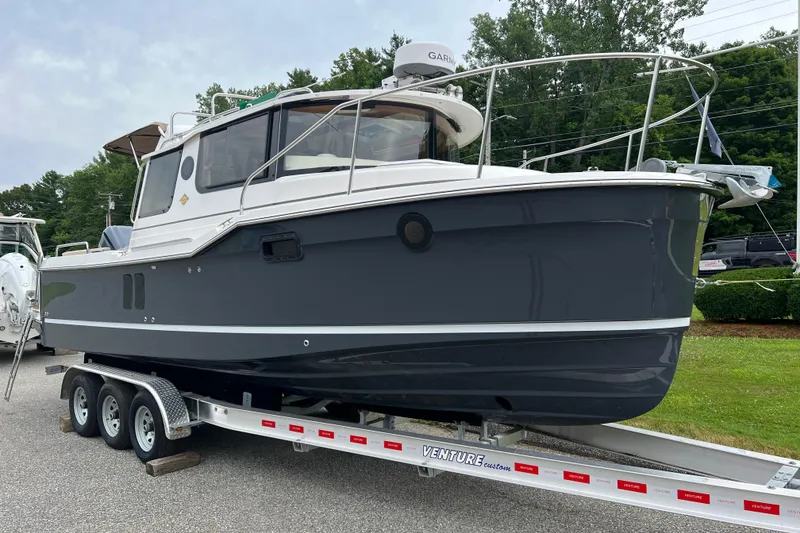 Slide: The Image of 2025 Ranger Tugs R-25 boat on trailer, displayed outdoors with lush greenery background. - 1