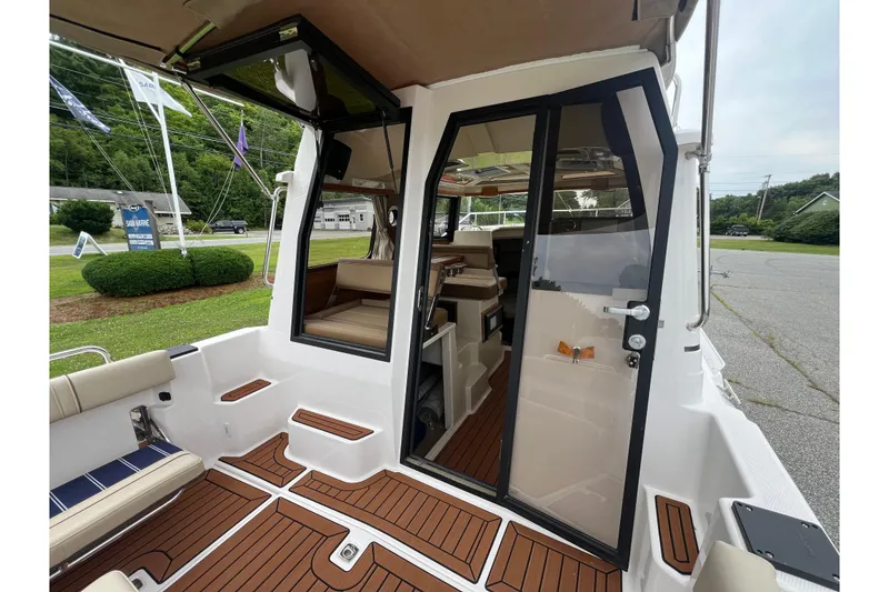 Slide: The Image of 2025 Ranger Tugs R-25 boat interior with open door, showcasing seating and wood flooring. - 10
