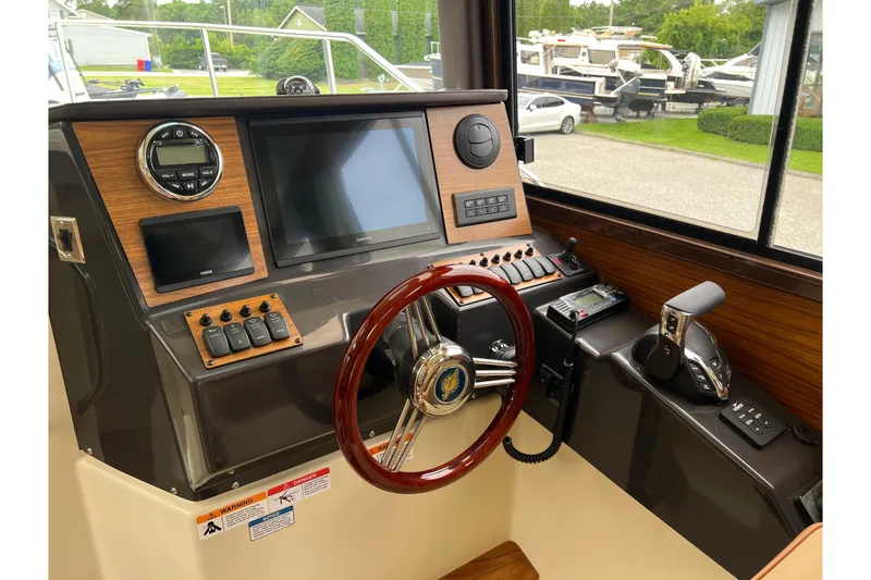 Slide: The Image of 2025 Ranger Tugs R-25 helm with modern controls and wood accents. - 17