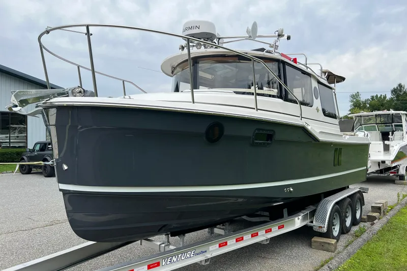 Slide: The Image of 2025 Ranger Tugs R-25 boat on trailer, parked outdoors near a building. - 2