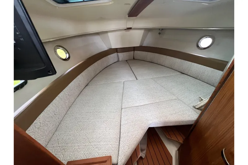 Slide: The Image of 2025 Ranger Tugs R-25 cabin interior with cozy seating and porthole windows. - 23