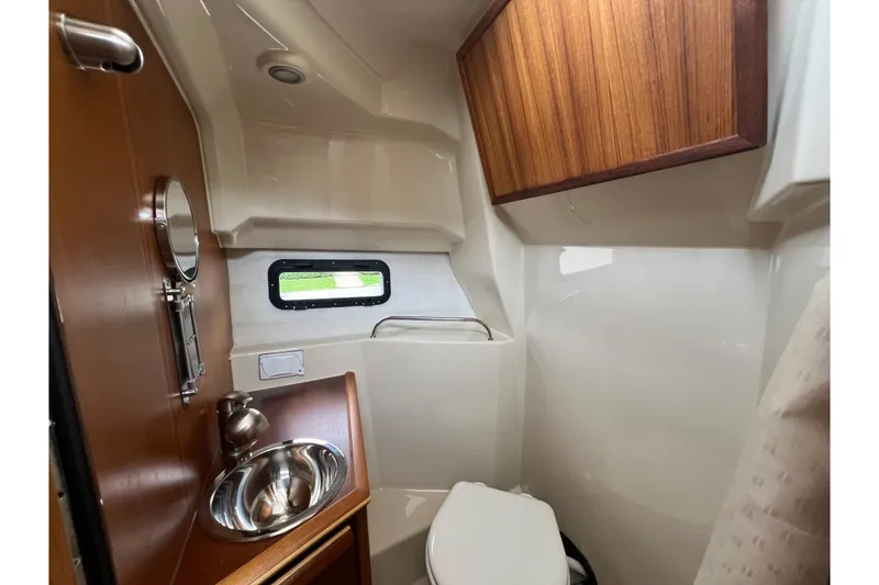 Slide: The Image of Compact bathroom in 2025 Ranger Tugs R-25 boat with sink, toilet, and wooden cabinet. - 26