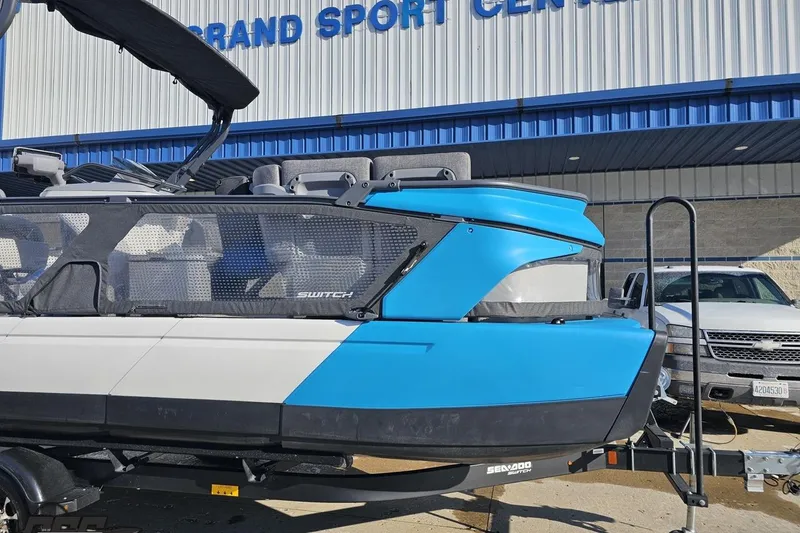 Slide: The Image of 2023 Sea-Doo Switch Cruise 21 pontoon boat in blue and white at dealership. - 14
