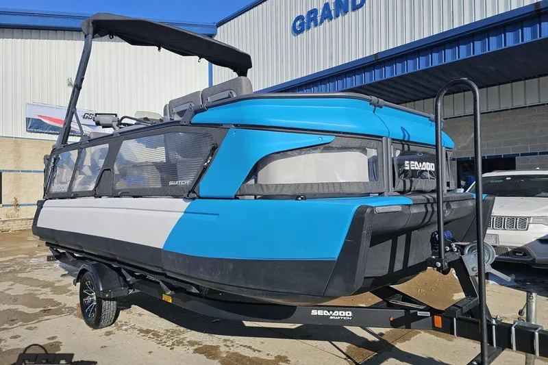 Slide: The Image of 2023 Sea-Doo Switch Cruise 21 pontoon boat on trailer, blue and white design. - 16